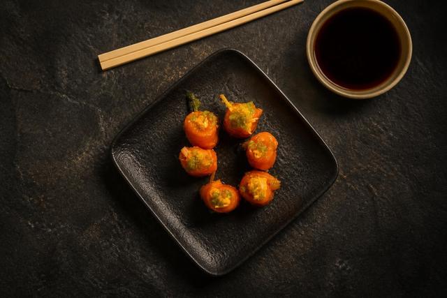 Salmon-wrapped bites topped with crab and green tobiko